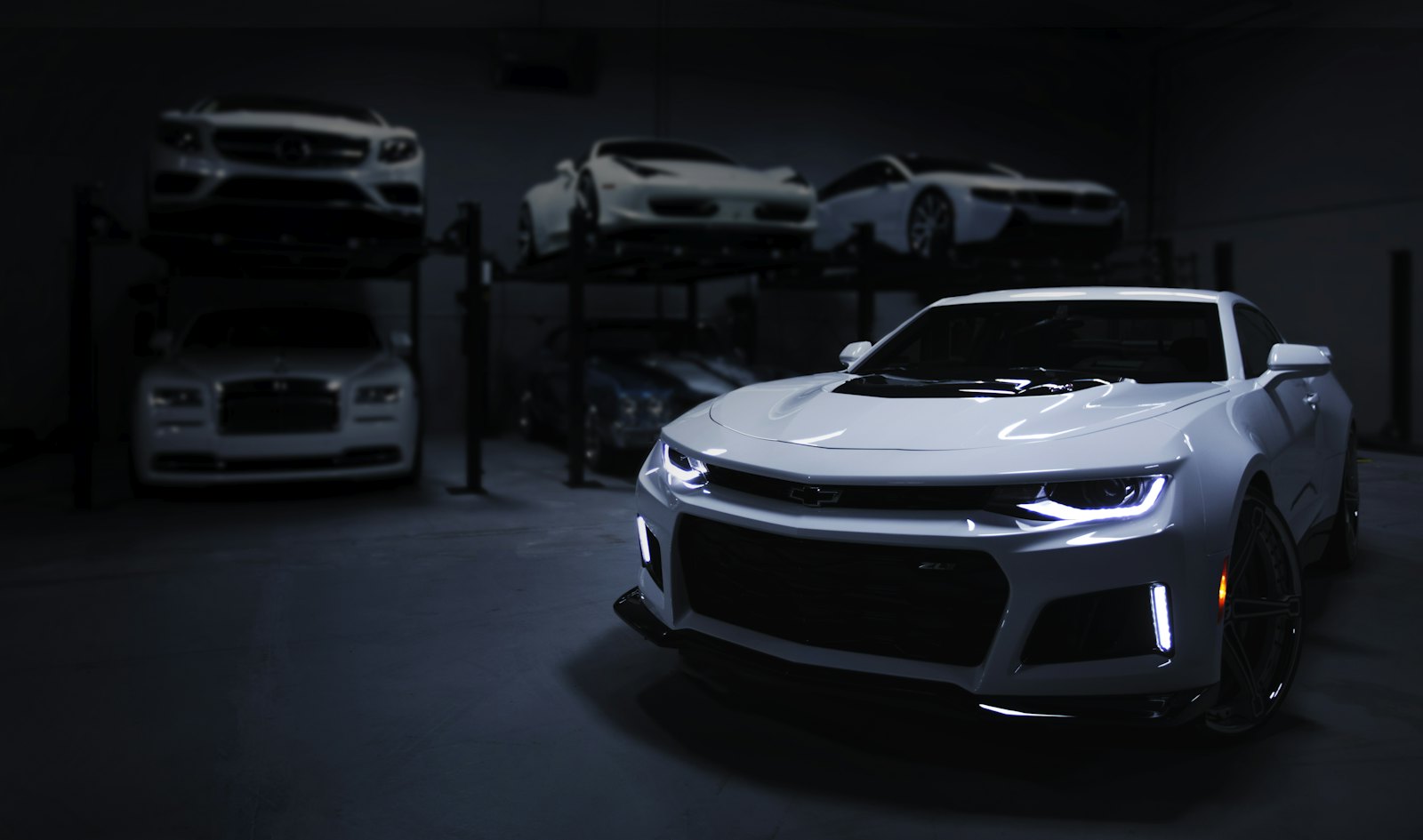 White cars parked on lifts in a dim garage